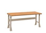 A rectangular wooden workbench with a light brown top and sturdy gray metal legs. The bench is set against a plain white background, showcasing its simple and functional design.