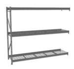 Industrial metal shelving with three wire mesh shelves is shown. The frame is made of sturdy metal beams, and there is ample space between each level for storage, suitable for warehouses or garages.