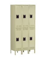 A beige metal locker unit with six compartments arranged in two vertical columns. Each locker has a ventilation grille at the top and bottom, and a black handle in the center. The unit stands on raised legs.