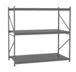 A large, industrial metal shelving unit with three tiers and a grey finish. The shelves are made of slatted metal, supported by sturdy vertical beams and braces. The backdrop is plain white.
