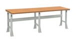 A long, rectangular workbench with a light brown wooden top and sturdy gray metal legs. The design includes a crossbar for added stability. The bench is suitable for various tasks and environments.