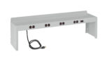 A gray metal power strip with multiple black outlets and a black power cord on the left end. It features a switch on the right side and is designed to mount on a surface. The device has a simple, industrial design.