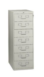 A tall, light gray filing cabinet with six drawers, each featuring a label holder and handle. The cabinet is slightly angled to the left, showing depth and structure.