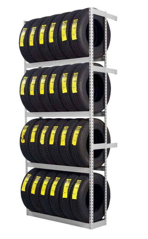 A metal shelving unit holds three rows of stacked black tires. Each tire has a yellow label on its tread, indicating specifications or pricing. The shelves are evenly spaced, and the setup appears organized and clean.