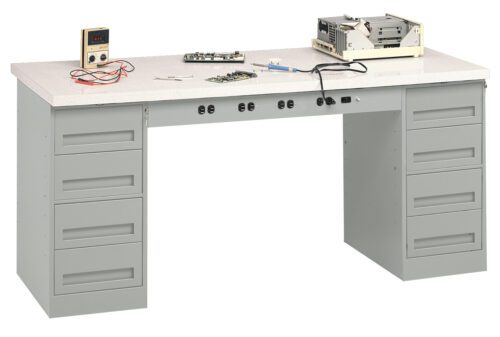 A large, gray workbench with multiple drawers. On top, there are electronic equipment, wires, a small digital display, and a circuit board. The setup suggests an electronics repair or assembly workspace.
