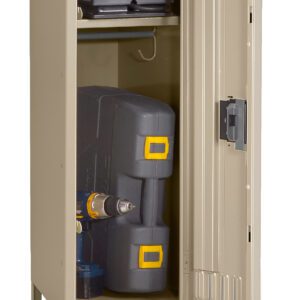 A beige metal storage locker with the door open, revealing a shelf with a black bag and a lower compartment holding a power tool box and a power drill placed upright. The locker stands on four legs.
