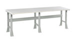 A long, rectangular white table with a sturdy, light gray metal frame and four angled legs. The design is simple and functional, suitable for various purposes like workspaces or utility areas.