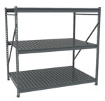 A gray metal shelving unit with three levels, featuring slatted shelves. The design is industrial and utilitarian, suitable for storage or warehouse use. The background is plain white, highlighting the structure.