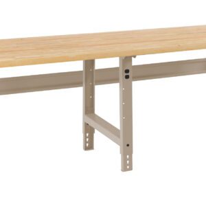 A long, sturdy workbench with a light wooden top and metal legs. The frame is painted in a beige color. The bench is designed for industrial or workshop use and rests on a solid surface.