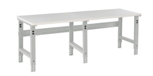 A long, rectangular white workbench with adjustable metal legs and support beams. The bench top has a smooth surface, and the legs have holes for height adjustment. The design is simple and functional, suitable for a workshop or garage.