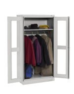 A white metal wardrobe with two open doors reveals several coats and jackets hanging on a rack. On the top shelf, there are hats and a small item. A blue bag is placed at the bottom of the wardrobe.