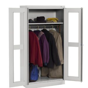 A white metal wardrobe with two open doors reveals several coats and jackets hanging on a rack. On the top shelf, there are hats and a small item. A blue bag is placed at the bottom of the wardrobe.