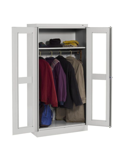 A white metal wardrobe with two open doors reveals several coats and jackets hanging on a rack. On the top shelf, there are hats and a small item. A blue bag is placed at the bottom of the wardrobe.