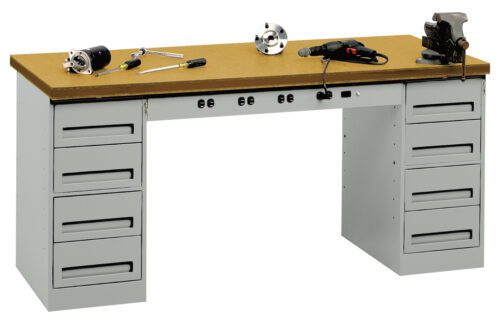 oxxfxbcmmp7blyrmej1o.jpg A metal workbench with a wooden top is shown, featuring several drawers on both sides. Various tools, including a drill, a wrench, and a clamp, are placed on the bench. A vise is mounted on the right side of the work surface.