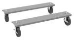 Two gray metal dolly skateboards with black wheels and locking mechanisms. Each has two wheels and a rectangular platform. Used for moving heavy furniture or equipment. Positioned diagonally with one behind the other.
