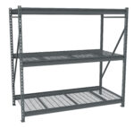 A large, empty metal shelving unit with three tiers and a grid pattern on the shelves. The structure is made of steel beams with diagonal support braces. The shelves are evenly spaced for storage. The unit is freestanding and industrial-style.