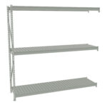 A grey, three-tiered metal shelving unit with slatted shelves is set against a white background. The shelves are supported by two vertical metal beams with holes for adjustable positioning. The unit is empty, displaying a minimalistic design.