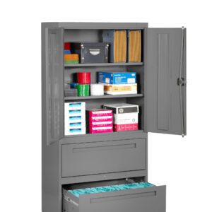 A tall grey metal storage cabinet with open doors shows various office supplies organized on shelves, including files, binders, envelopes, and boxes. Two lower drawers are partially open, containing hanging file folders.