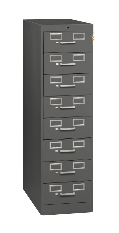 Tall, dark gray file cabinet with six drawers, each featuring a rectangular label holder and handle. A small lock is visible on the top drawer. The cabinet stands on a plain white background.