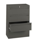 A tall, dark gray metal filing cabinet with three drawers. The top drawer is closed and has a key in the lock, while the middle drawer is also closed. The bottom drawer is partially open, revealing sliding rails inside.