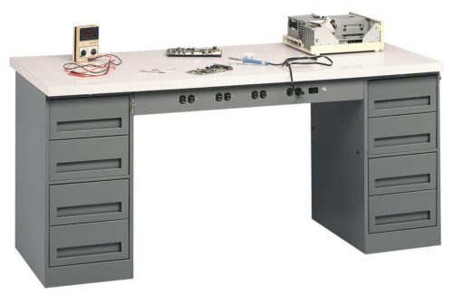 A gray workbench with multiple drawers, featuring a digital multimeter, circuit board, tools, and electronic equipment on top. The workbench has a smooth surface and power outlets underneath.
