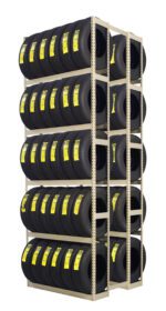 A tall, multi-tiered metal rack holds numerous black tires. Each tire has a yellow label affixed to its tread. The rack is organized neatly in vertical columns and horizontal rows, displaying the tires in a warehouse or storage setting.