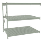 A gray metal storage rack with three shelves. The structure is sturdy with vertical supports and horizontal brackets. The shelves are evenly spaced and ribbed for added strength, suitable for holding various items in a warehouse or garage.