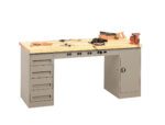 A workbench with a wooden top, featuring attached drawers and a cabinet. Various tools, including a saw, hammer, and clamps, are placed on the surface. The structure is grey metal with a light wood top.