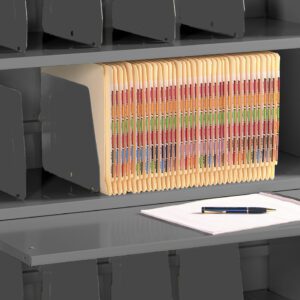 Metal shelving unit filled with vertical file folders organized by colored labels. A lower pull-out shelf holds a stack of white papers with a pen placed on top.