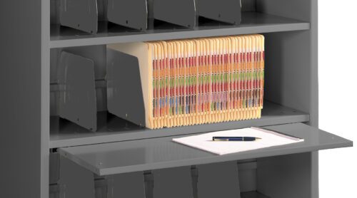 Metal shelving unit filled with vertical file folders organized by colored labels. A lower pull-out shelf holds a stack of white papers with a pen placed on top.