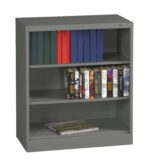 A gray metal bookshelf with three shelves. The top shelf has blue and red binders, the middle shelf displays various Stephen King novels, and the bottom shelf has a closed book.
