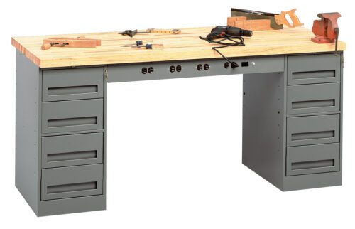 A sturdy workbench with a wooden top and gray metal drawers on both sides. Various woodworking tools, including a saw, clamp, drill, and measuring tape, are placed on the surface. A row of electrical outlets is visible beneath the tabletop.