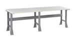 A long, sturdy workbench with a light gray tabletop and metallic gray legs. The design features a support beam across the length underneath the table. Ideal for workshops or industrial settings.