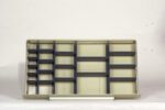 Empty metal shelving unit with multiple horizontal and vertical dividers against a plain background. The shelves are beige with dark gray edges and brackets.