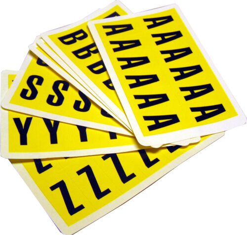 A stack of MH-USA Complete Packs of Self-Adhesive Letters - H.0.83 in. x W.1.5 in. - features black uppercase letters on yellow sheets like A, B, S, Y, and Z, arranged in an overlapping fan-like style to add creativity to any project.