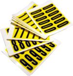 A stack of MH-USA Complete Packs of Self-Adhesive Numbers in yellow, featuring bold black digits like 0s, 1s, 8s, and 9s on each card. Measuring H.0.83 in. x W.2.2 in., these numbers ensure clear visibility.