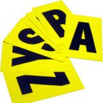 A scattered stack of MH-USA Complete Packs of Self-Adhesive Letters in vivid yellow, featuring large black letters like A, R, S, Y, and Z, are spread out on a flat surface. Each card measures 5.51 inches by 9.06 inches.