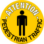 A yellow circular MH-USA Floor Graphic Marker, featuring a black silhouette of a person, displays ATTENTION PEDESTRIAN TRAFFIC for safety emphasis. The marker, measuring 16.93 inches in diameter, ensures high visibility.