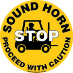 The MH-USA Floor Graphic Marker, 16.93 inches in diameter, is a yellow circle with a black silhouette of a forklift and driver and the message SOUND HORN STOP PROCEED WITH CAUTION, promoting safety by urging careful movement.