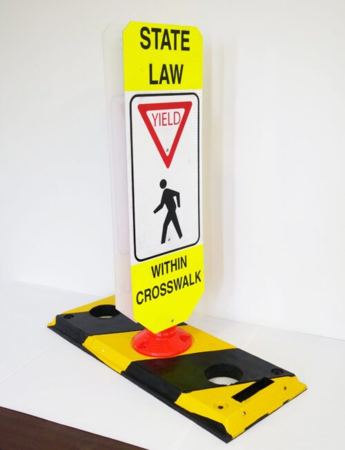 The TCT Flexible Post Crosswalk System, State Law - Yield features a sign on a yellow/black base that reads State Law: Yield to Pedestrians Within Crosswalk, with a pedestrian symbol and yield triangle, set against a plain white background for enhanced visibility.