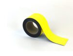 An MH-USA Magnetic Easy-Wipe Strip in vibrant yellow is on a light surface, partially unrolled to highlight its color against the black underside. It measures H.2.76 in x W3.94 in and is ideal for various uses.