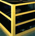 A yellow metal safety railing on a platform surrounds a dark area below, much like an efficient workspace organization design. The railing, with vertical and horizontal bars secured by bolts, stands firmly on the textured metal surface.