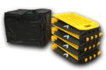 A set of four vertically stacked black and yellow traction boards with textured surfaces and carrying handles, plus a black bag, offer stability and convenience like the TCT Hinged Portable Speed Bump (8 sections, Black/Yellow, 118L x 9.75W x 1H) for versatile use.