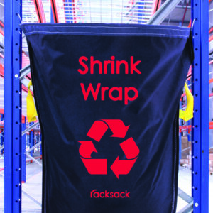 The MH-USA Racksack - Shrink Wrap, in black, features a red recycling symbol and is attached to a metal frame. Clearly branded as racksack, it stands out in a well-lit industrial setting for efficient and visible recycling.