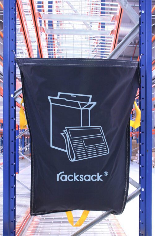 RSB1MPNT.jpg A blue MH-USA Racksack for Mixed Paper and Card hangs on a warehouse metal shelf, featuring a white cardboard box and newspaper icon with yellow side handles.