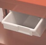 A white plastic drawer partially open, installed under a wooden or metal surface. The surrounding area is a shade of light brown or orange. The drawers front has a small recessed handle on the right side.