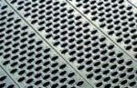 Close-up of a metallic surface with rows of evenly spaced oval holes, creating a patterned texture reminiscent of a custom catwalk system. The lighting highlights the ridges and depth of the perforations, evoking a sense of industrial design.