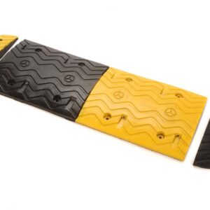 The TCT 5-10 MPH Speed Bump features a modular design with alternating yellow and black sections on a white background. Each section is 15 wide, 39.5 long, and 2 tall with a zigzag pattern, bolted together using half-circle end pieces.
