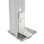 Close-up of a metallic bolt and bracket assembly attached to a pole. The structure is mounted on a flat, square base. The metal components have a silver finish, and the setup appears industrial or structural, suitable for construction purposes.