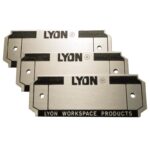 Three metal nameplates with the text LYON in bold black letters. Below, LYON WORKSPACE PRODUCTS is printed in smaller text. Each nameplate has two holes for mounting. The design features a rectangular and angular style.